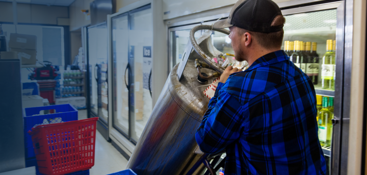 CO2 tank being rolled out of a convenience store by a man.