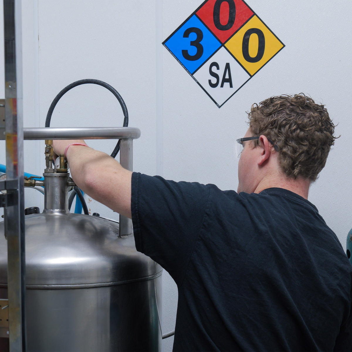 Person working with CO2 tank, with hazmat signage.