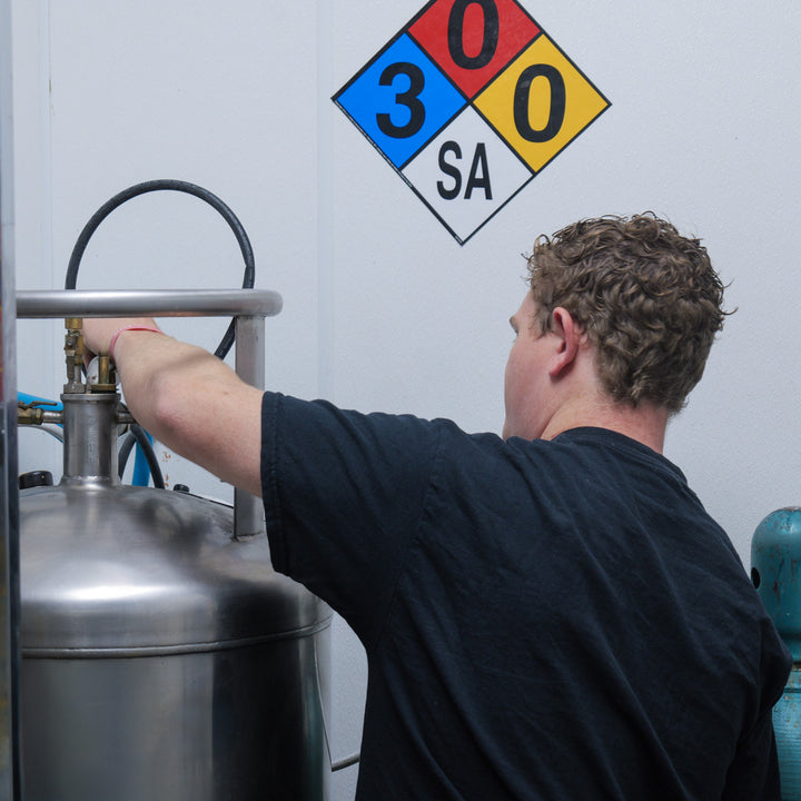Person working with CO2 tank, with hazmat signage.